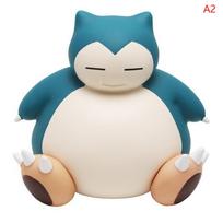 „Pokemon Snorlax Money Box 2“ poza figūrėlė, stovinti sėdinčioje taupyklėje