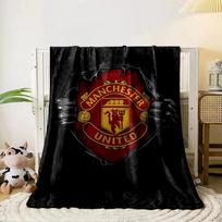 A red and gold Manchester United emblem revealed through ripped black fabric. for all seasons blanket lunch break throw gift 80cm x 120cm