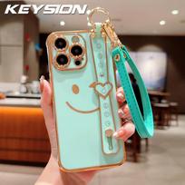 KEYSION Wrist Strap Smiley Face Phone Case for iPhone 13 14 15 16 17 Pro Max 17 Air 16e 16 Plus Plating Silicone Lanyard Shockproof Cover for iPhone 17 mėtinė