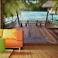 Fototapetas Artgeist Tropical Landscape - Turquoise water with palm trees and wooden cottages XXLNEW010218, 210 cm x 300 cm